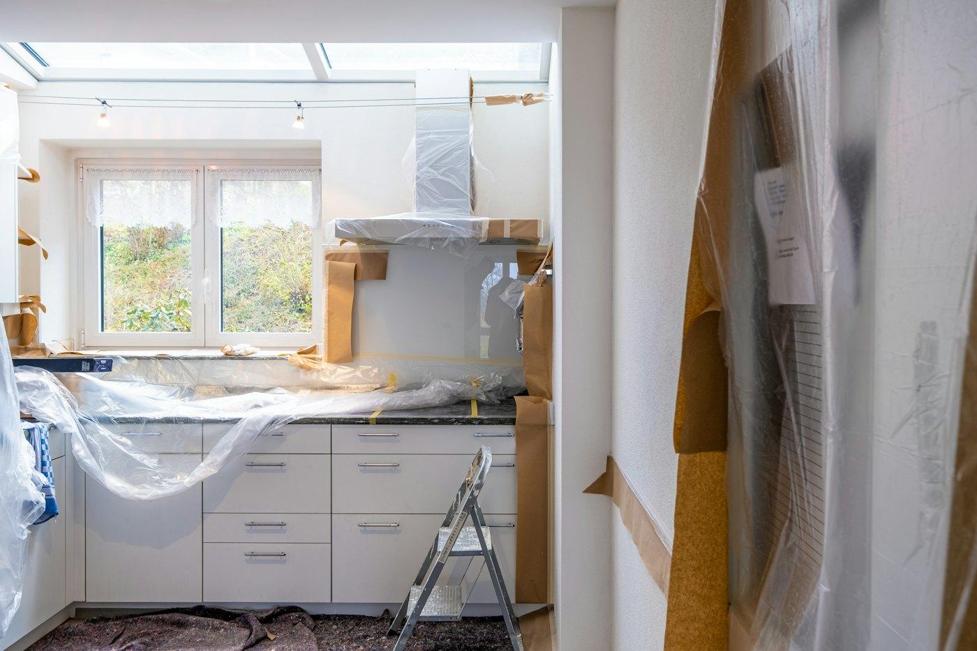 Kitchen mid-renovation with new cabinetry under protective wrap