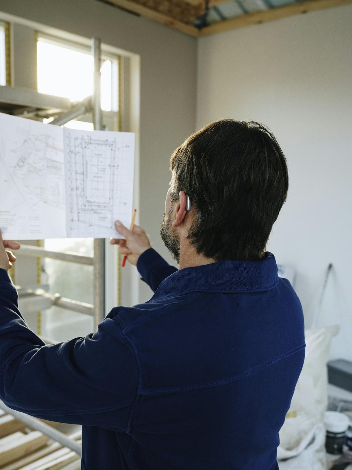 Builder reviewing construction drawings inside a home under construction