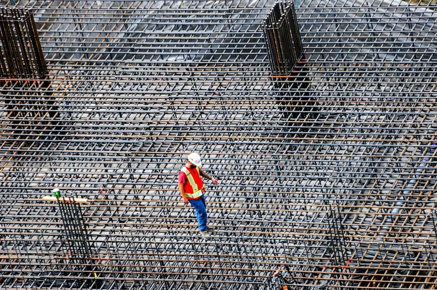 Workers tying steel reinforcement across a large concrete slab, seen from above