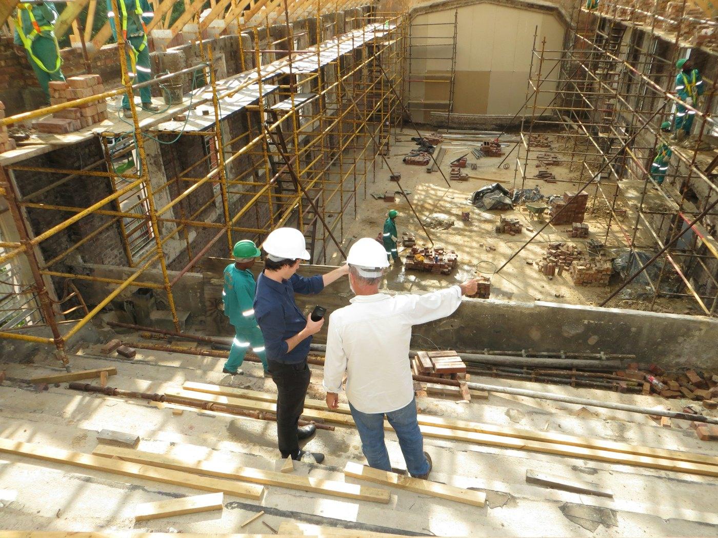 Two builders in hard hats discussing work on a construction site